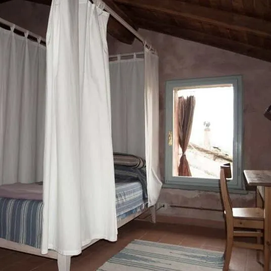 Slaapkamer onder een schuin balkenplafond, met bedden achter gordijnen