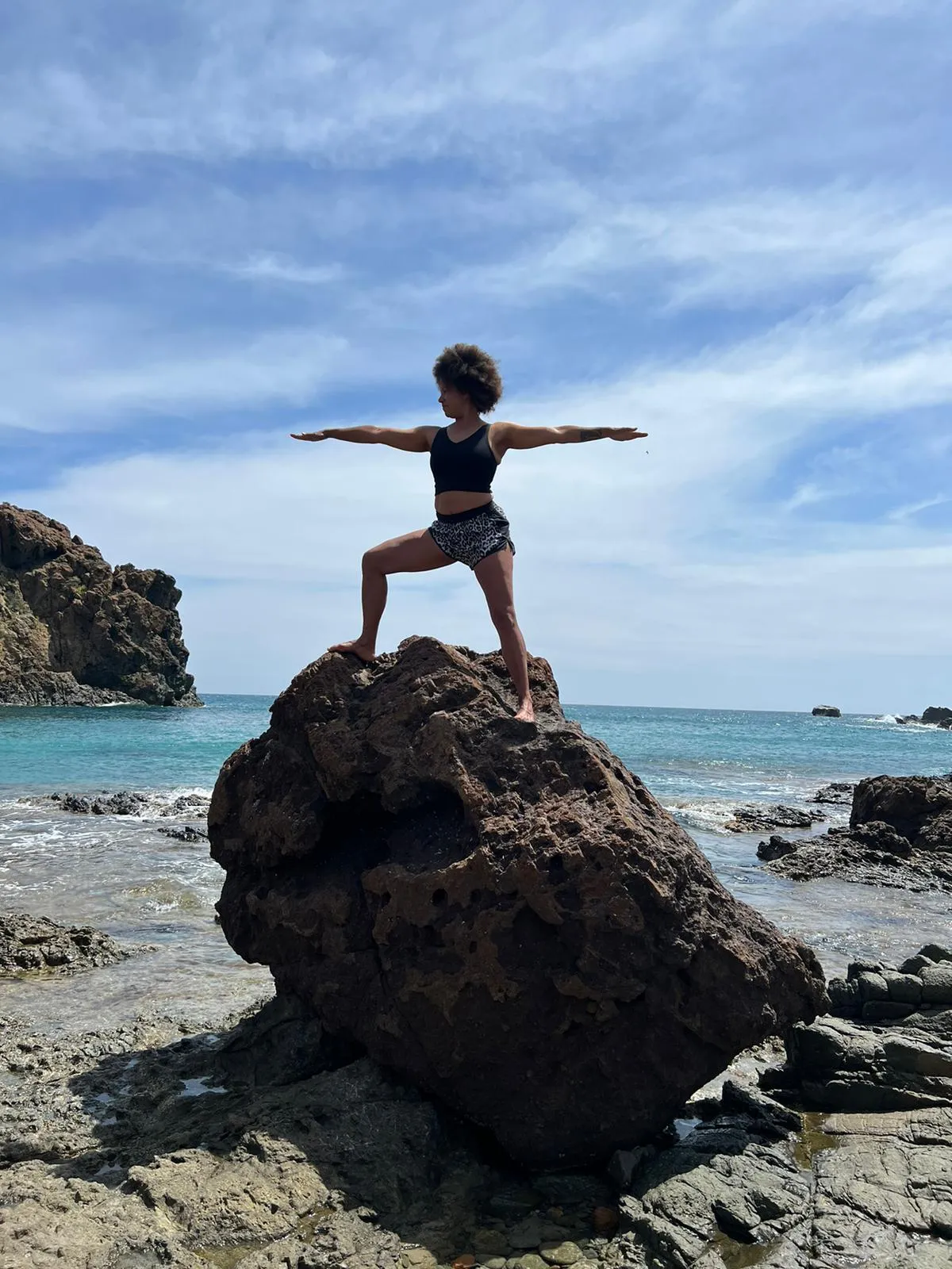 Vrouw in een yogahouding op een rots aan zee