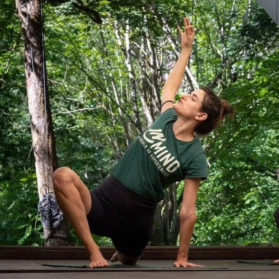 Vrouw in een yogahouding op een houten vlonder in het bos
