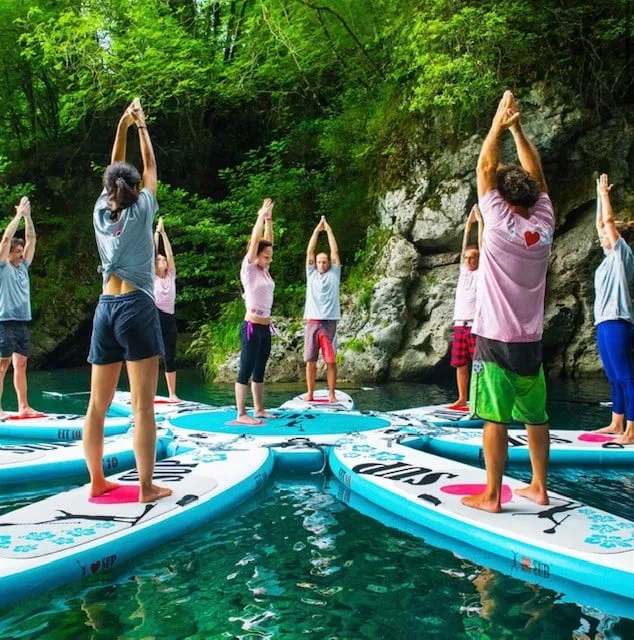 Groep mensen in een yogahouding op supboards, in een kring op het water